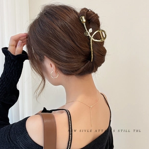 Detailed close-up of a golden rose metal hair claw clip styled on a low bun hairstyle