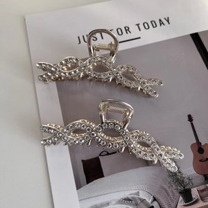Detailweergave van twee zilveren haarklemmen met strass-steentjes op een modetijdschrift
