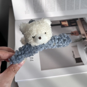 Close-up of white plush bear hair claw clip with blue fuzzy fabric texture detail