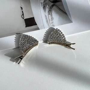 Vue détaillée de barrettes à cheveux dorées avec des strass étincelants en forme d'oreilles