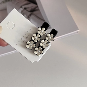 Détail de deux barrettes camélia en acétate avec perles sur carte de présentation