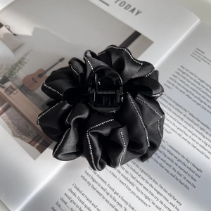 Elegant black satin flower hair claw clip with rhinestones shown on a fashion magazine