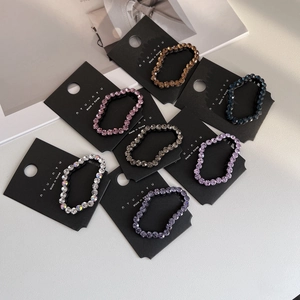Macro detail of seven colorful rhinestone elastic hair ties displayed on branding cards