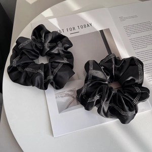 Elegant set of two black satin scrunchies with sparkling rhinestone stripes on a white table