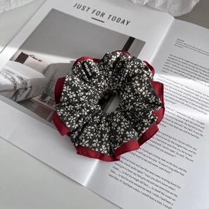 Detailed close-up of a floral scrunchie with grey flower pattern and red inner fabric layer