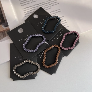 Close-up of five colorful crystal-encrusted hair ties on a minimalist display card