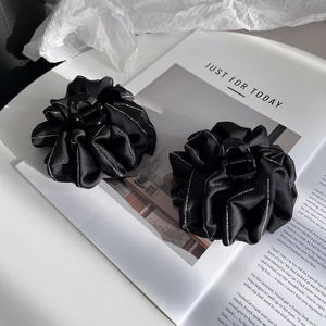 Close-up of elegant black fabric flower hair claw clip with sparkly silver rhinestones