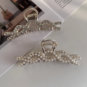 Elegante set metalen haarklemmen met strassteentjes en parels op witte tijdschrift achtergrond