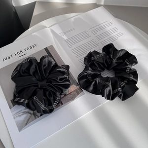 Detail showing two black satin scrunchies with rhinestones on a magazine