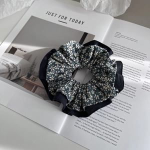 Detailed view of blue floral hair scrunchie with layered lace design on magazine backdrop