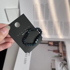 Detailed view of handmade dark blue beaded hair clip on a black card from a close-up perspective