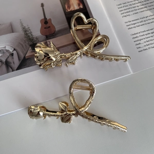 Close-up of golden metal rose and heart hair claws on an open magazine page