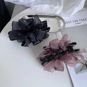 Détail de la pince à cheveux avec nœud en organza élégant et bords en cristaux brillants