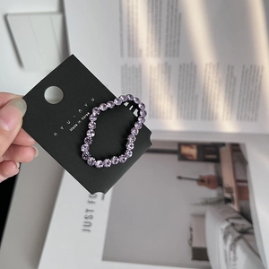 Detail of hand-held lavender crystal hair clip with shiny rhinestones on display card