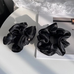 Detail of two black satin scrunchies with sparkling rhinestone trim for elegant hairstyles
