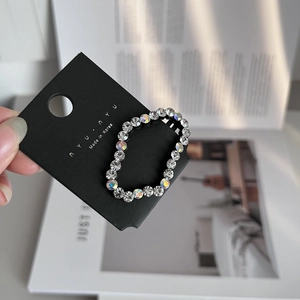 Close-up of cloud-shaped hair clip with sparkling Czech rhinestones on black base