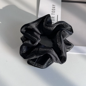 Elegant black satin scrunchie with sparkling silver rhinestone stripes on white background