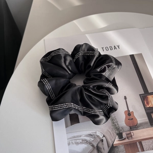 Detail of black satin scrunchie with sparkling double-row rhinestone edges on a book