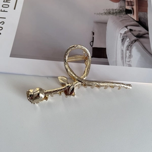 Close-up of golden rose metal hair claw clip with detailed floral textures and glossy finish