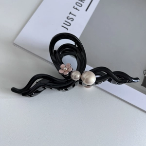 Detail of a large black claw clip featuring a pink flower and elegant pearls decoration