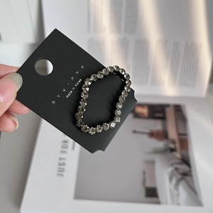 Detail of grey rhinestone hair ring on display card showing sparkling faceted crystals