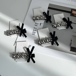 Detailed macro view of black bow hair clips with rhinestones on a display card
