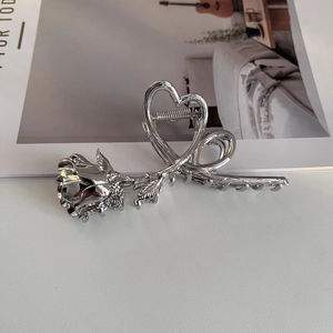 Detail view of the silver rose and double heart-shaped metal hair claw clip with mirror finish