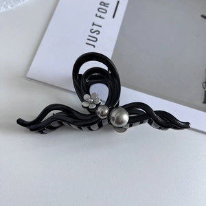 Detail of elegant black resin hair claw clip with silver flower and bead accents