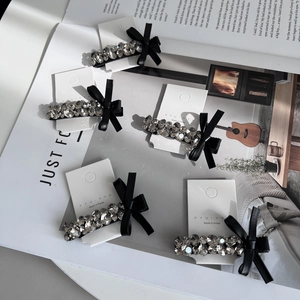 Five-piece set of elegant rhinestone hair clips with black leather bows on a white board