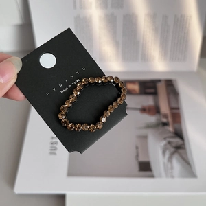 Close-up of amber crystal beaded hair clip on branded card with natural lighting