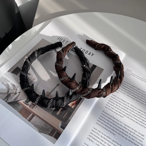 Detail view of rhinestone-studded headbands in black and brown over a fashion magazine