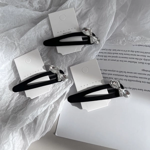 Detailed view of elegant black fabric BB clips with sparkling crystal rhinestone bows