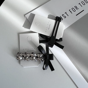 Elegant set with black bow hair clip and sparkling rhinestone silver barrette on display card