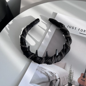 Detail of handmade black satin headband with sparkling rhinestones and punk style spikes
