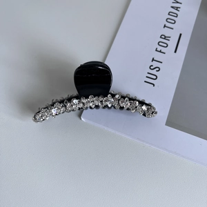 Dettaglio di un fermaglio per capelli nero con strass scintillanti su pelle bianca