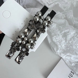 Detailed macro view of two luxury dark grey rhinestone and pearl hair clips set
