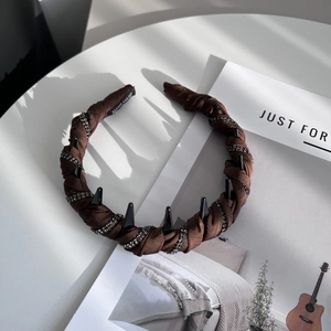Macro shot of dark brown fabric headband with black spikes and rhinestone details