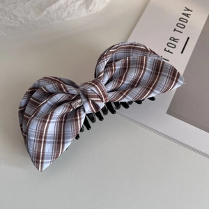 Close-up of brown and blue checkered fabric hair claw clip with small metal logo plate