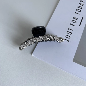 Dettaglio di un'elegante pinza per capelli nera con doppie file di cristalli lucidi