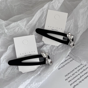 Detail of matte black BB clips featuring sparkling crystal bow accents on display card