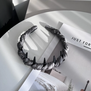 Detail of grey satin headband with black acrylic spikes and sparkling rhinestone lines