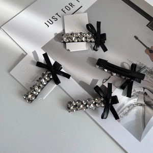 Close-up of elegant black bow hair clip with sparkling rhinestones on brand card