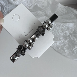 Detail of luxury rhinestone hair clip with grey crystals and pearls on branding card