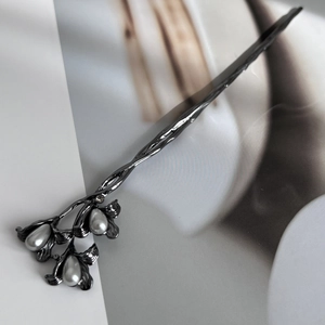 Close-up of black metal hair stick featuring delicate flowers and teardrop pearls