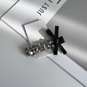 Detail of crystal rhinestone hair clip with a black bow on a white display card