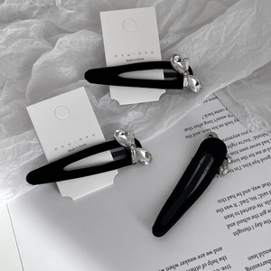 Three-piece black BB clip set with crystal butterfly knots on elegant paper background