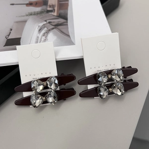 Vue détaillée des barrettes en résine rouge foncé avec des nœuds en strass brillants
