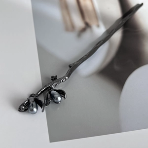 Detailed 45-degree view of a metal flower hair pin with elegant grey pearls