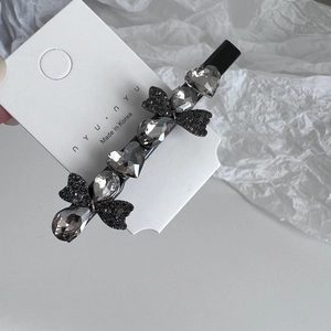 Close-up of grey crystal rhinestones and black glitter bows on a stylish hair clip