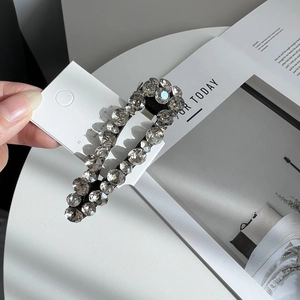 Macro detail of Korean rhinestone hair clip with large clear crystals and black metal base
